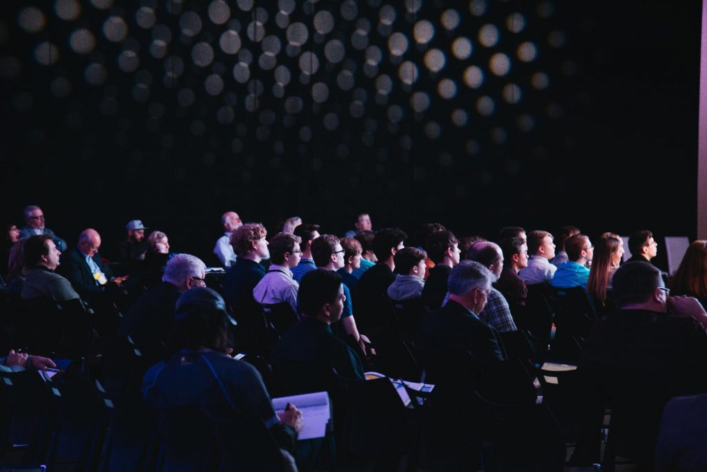 A dimly lit room full of people seated